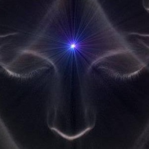 Può includere: Un primo piano di un viso con gli occhi chiusi. Una luce blu brillante splende dal centro della fronte.