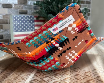 Peut inclure: Un protège-bol en tissu marron avec un motif géométrique coloré en rouge, orange, turquoise et blanc. Le protège-bol est fait à la main et porte une étiquette indiquant "Handmade by FLPatriotProvisions."