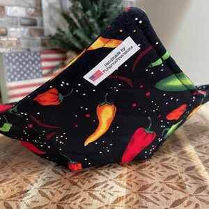 Könnte beinhalten: Eine schwarze Stoffschale mit einem Muster aus roten, orangen und grünen Chilischoten. Die Schale hat ein weißes Etikett mit der Aufschrift "Handmade by FLPatriotProvisions".