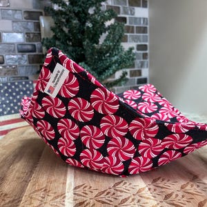 Puede incluir: Un par de salvabols de tela con fondo negro y un estampado de caramelos de menta poivrée rojos y blancos. Los salvabols están hechos a mano y tienen una etiqueta que dice "Handmade by FLDenceProvisions".