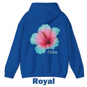 May include: A royal blue hooded sweatshirt featuring a large hibiscus flower graphic on the back. The flower has pink and teal petals with a yellow stamen. The word Aloha is printed in a white script font below the flower. The text Royal is below.