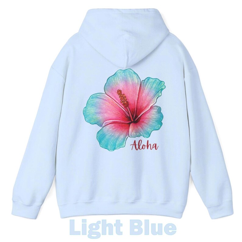 May include: A light blue hooded sweatshirt featuring a large, colorful hibiscus flower graphic on the back. The flower displays a gradient of pink and teal hues. Below the flower, the word Aloha is printed in a dark red, cursive script font.