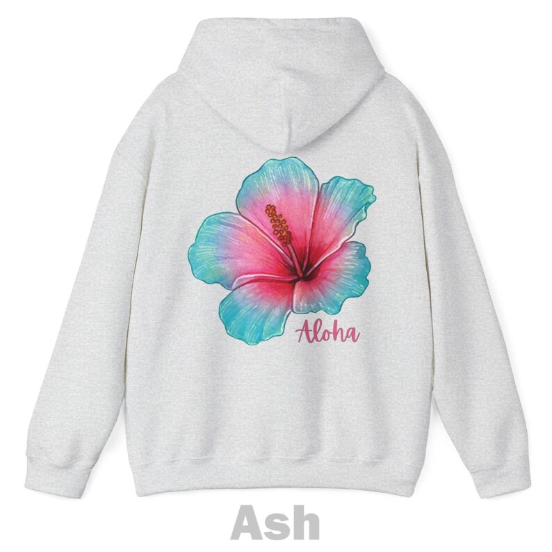 May include: A light gray ash-colored hooded sweatshirt featuring a large hibiscus flower graphic on the back. The flower displays a gradient of pink and teal colors. The word Aloha is printed in a cursive pink script below the flower.