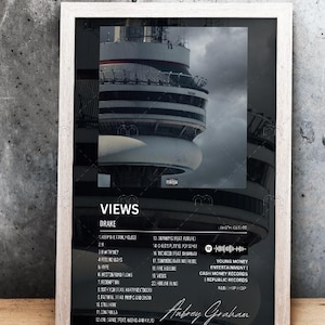 May include: A black and white album cover for Drake's album "Views". The cover features a photo of the CN Tower in Toronto, Canada. The album title and artist name are in white text at the top of the cover. The tracklist is listed in white text on the left side of the cover. The album credits are listed in white text on the right side of the cover. The album cover also includes a barcode and a Spotify logo.