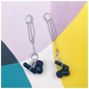 May include: A pair of black wireless earbuds with silver chains attached to the earpieces. The chains are connected to silver hoops.