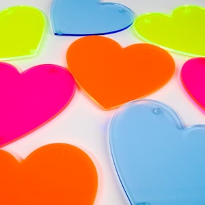 May include: Seven neon heart-shaped acrylic coasters in various colors, including pink, orange, yellow, and blue.