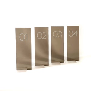 May include: Four brown table number signs with white numbers. The numbers are 01, 02, 03, and 04.