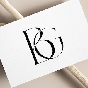 May include: A white card with a black monogram of the letters "B" and "G" intertwined.