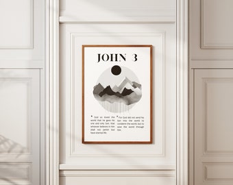 Op de afbeelding: Een minimalistische zwart-wit kunstprint met een bergketen en een cirkel met een zwarte zon. De print bevat de tekst "JOHN 3" en een bijbelvers: "Want God heeft de wereld zo liefgehad, dat Hij Zijn eniggeboren Zoon gegeven heeft, opdat een ieder die in Hem gelooft, niet verloren gaat, maar eeuwig leven heeft. Want God heeft Zijn Zoon niet in de wereld gezonden om de wereld te veroordelen, maar opdat de wereld door Hem gered worde."