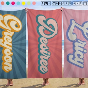 May include: Three beach towels with personalized names. The first towel is blue with the name "Greyon" in orange and white. The second towel is pink with the name "Desiree" in teal and white. The third towel is pink with the name "Lucy" in blue and white. The text "15+ COLORS ANY TEXT" is at the top.
