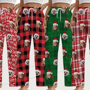 Könnte beinhalten: Vier Paar Schlafanzughosen in verschiedenen Weihnachtsmustern. Die Hosen zeigen ein sich wiederholendes Muster aus dem Gesicht einer Person und dem Gesicht eines Hundes mit Weihnachtsmützen. Zu den Mustern gehören Rot mit "Ho-Ho-Ho"-Text, rot-schwarzes Büffelkaro, grünes Karo und rotes Karo.