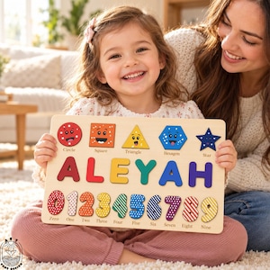 May include: A wooden puzzle board featuring the name ALEYAH in large, colorful letters. Above the name are five shapes with faces labeled Circle, Square, Triangle, Hexagon, and Star. Below are numbers zero through nine with patterns.