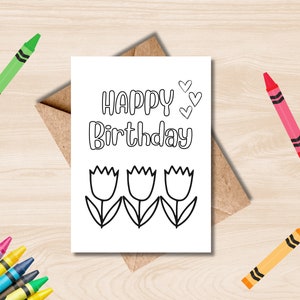 Pode incluir: Um cartão de colorir em branco com o texto "Happy Birthday" e três tulipas. Há também três pequenos corações acima do texto.
