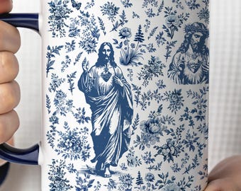 May include: White ceramic mug with a blue floral pattern and images of Jesus. The mug has a dark blue handle and rim. The design includes a central image of Jesus and a smaller image of Jesus wearing a crown of thorns.