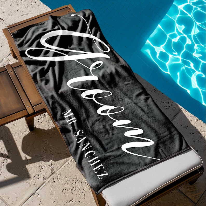 May include: Black beach towel with the word "Groom" written in white cursive script. The text "MR. SANCHEZ" is written in white below the word "Groom".