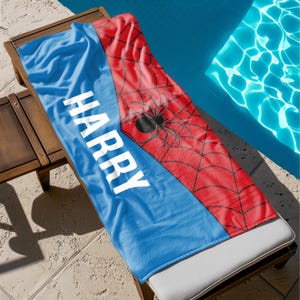 May include: A blue and red beach towel with a spider web design and the name "HARRY" printed in white.