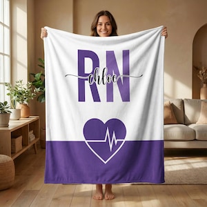 May include: White blanket with a purple RN design and the name "Chloe" in cursive script. A purple heart with a white EKG line is at the bottom. The blanket is held up by a person.
