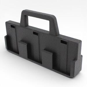 May include: A black plastic carrying case with a textured surface. The case has a handle and several rectangular cutouts and protrusions. The design suggests it is for organizing or transporting items.