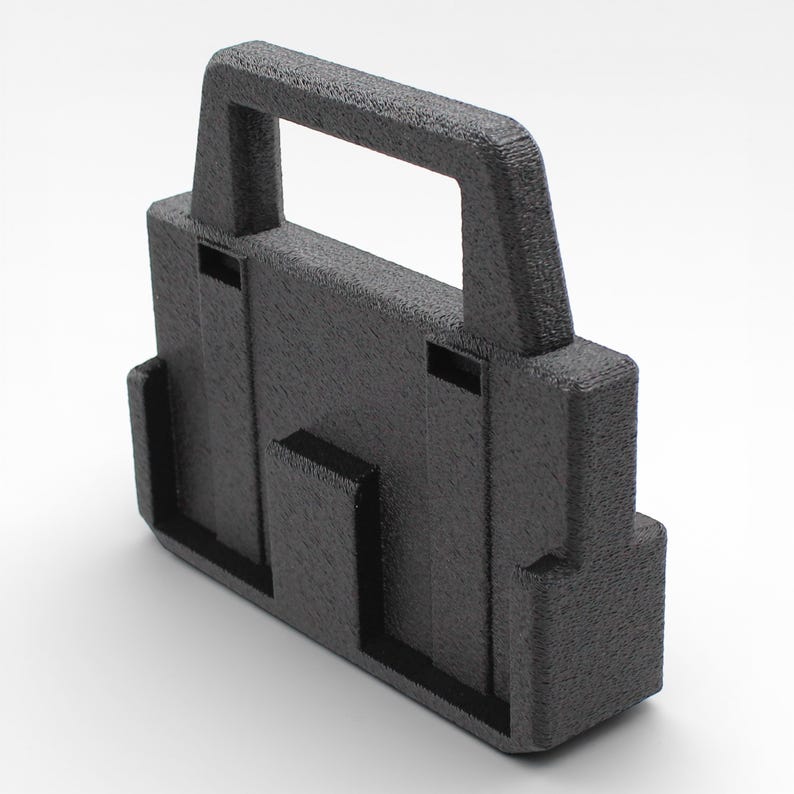 May include: A dark gray, rectangular carrying case with a handle. The case has a textured surface and features two recessed areas on the front and side. The handle is integrated into the top of the case, providing a secure grip.