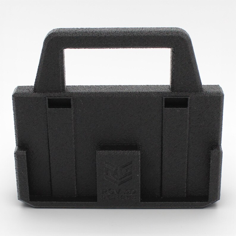 May include: A black, rectangular 3D-printed object with a handle and a rectangular opening. The object has a textured surface and a small rectangular logo on the front. The object has two vertical slots on the front.