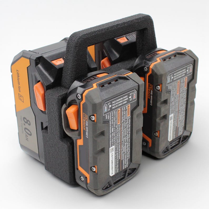 May include: A black and orange Lithium Ion battery pack with a handle. The pack has a capacity of 8.0 Ah. The battery pack is designed for power tools. The pack has a black and orange color scheme.