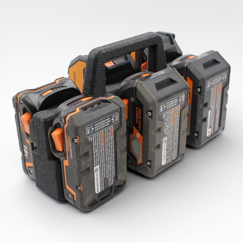 May include: A black and orange battery holder with four 18V Lithium-Ion batteries. The holder has a black handle and orange accents. The batteries are gray and black with orange buttons.
