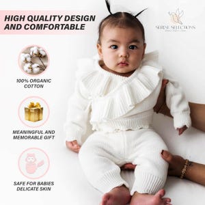 May include: A white knitted baby outfit with a ruffled top and matching pants. The outfit is made of 100% organic cotton and is safe for babies' delicate skin. The text "HIGH QUALITY DESIGN AND COMFORTABLE" is at the top of the image. The text "100% ORGANIC COTTON" is in a pink box with a white cotton ball image. The text "MEANINGFUL AND MEMORABLE GIFT" is in a pink box with a gold gift box image. The text "SAFE FOR BABIES DELICATE SKIN" is in a pink box with a baby image. The text "SERENE SELECTIONS" is at the top right of the image.