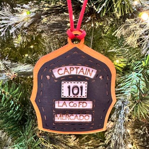 Puede incluir: Un letrero de madera rústico blanco con la palabra "Welcome" escrita a mano. Presenta un diseño floral decorativo en la esquina. El fondo es una imagen borrosa de una pared de madera, dando un aspecto envejecido.