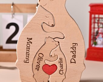 Puede incluir: Un rompecabezas de madera de una familia de osos con las palabras "Mamá", "Papá", "Oliver" y "Charlie" grabadas. Un corazón rojo está en el centro. El rompecabezas es de color marrón claro y tiene un acabado liso. Un calendario muestra el 2 de abril.