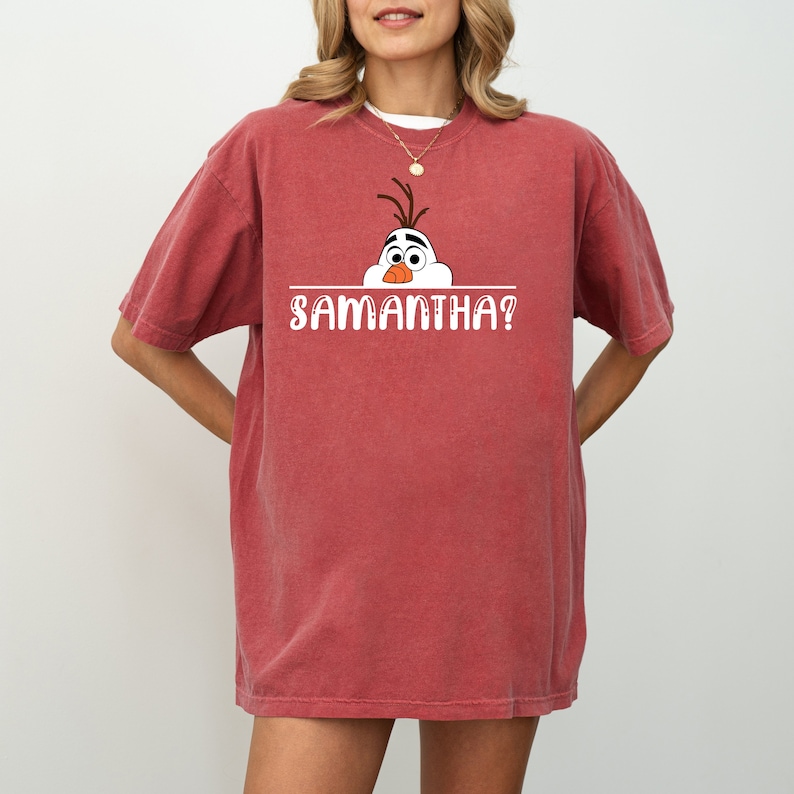 Puede incluir: Camiseta roja con un gr&aacute;fico blanco de Olaf de Frozen asom&aacute;ndose por encima de una l&iacute;nea con el texto "SAMANTHA?"