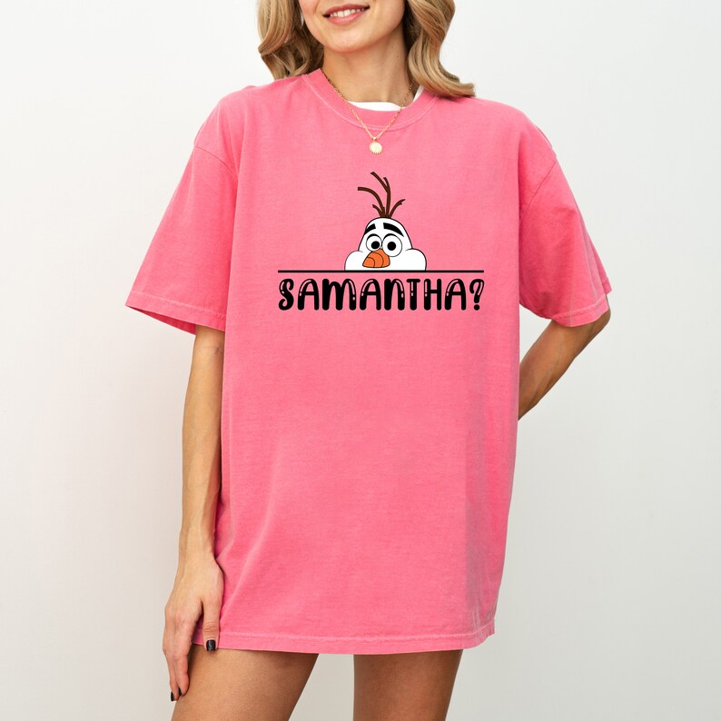 Puede incluir: Camiseta rosa con un mu&ntilde;eco de nieve de dibujos animados asom&aacute;ndose sobre el texto "SAMANTHA?"