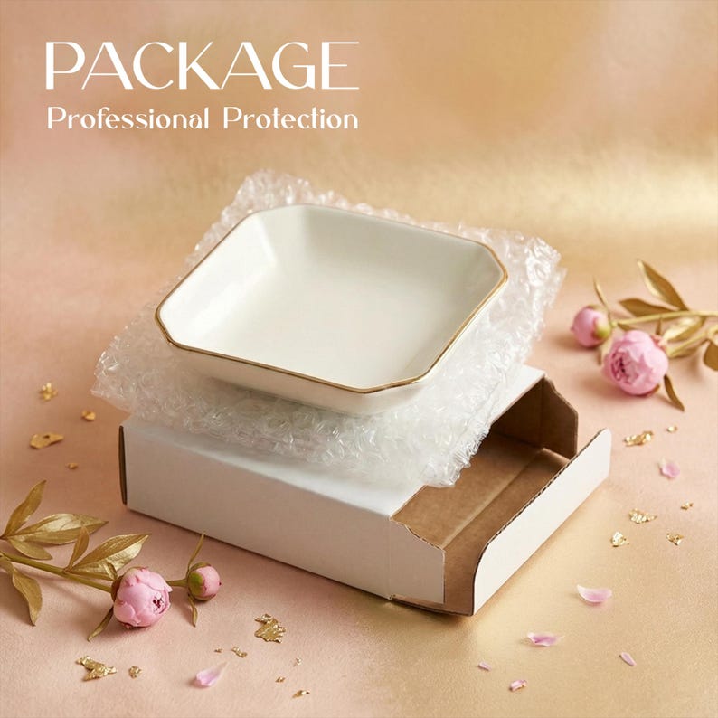 May include: A white square dish with gold trim rests on bubble wrap inside a white cardboard box. The image includes text that reads "PACKAGE Professional Protection". Pink flowers and gold leaf accents are scattered around the box.