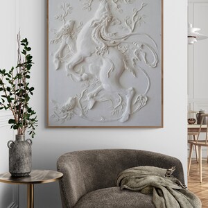 Puede incluir: Una escultura de pared 3D blanca de un caballo con un p&aacute;jaro posado en una rama. La escultura est&aacute; enmarcada en un marco de madera claro y cuelga de una pared blanca.