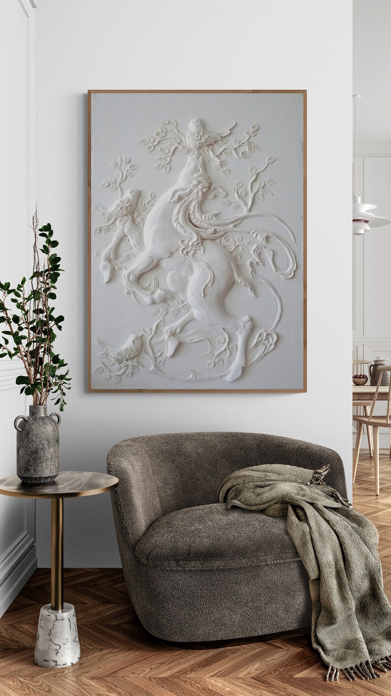 Puede incluir: Una escultura de pared 3D blanca de un caballo con un p&aacute;jaro posado en una rama. La escultura est&aacute; enmarcada en un marco de madera claro y cuelga de una pared blanca.