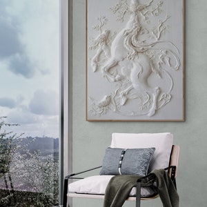 Puede incluir: Una escultura de pared 3D blanca de una criatura m&iacute;tica con un p&aacute;jaro posado en su cabeza. La escultura est&aacute; colocada sobre un fondo verde claro y est&aacute; enmarcada en un marco de madera claro.