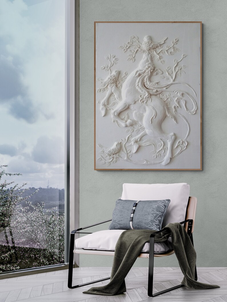 Puede incluir: Una escultura de pared 3D blanca de una criatura m&iacute;tica con un p&aacute;jaro posado en su cabeza. La escultura est&aacute; colocada sobre un fondo verde claro y est&aacute; enmarcada en un marco de madera claro.