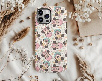 May include: A phone case with a repeating pattern of Minnie Mouse dressed as an Easter bunny. The design features pink, yellow, and blue accents on a cream background. Carrots and stars are also included in the pattern.