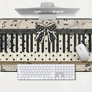 May include: A rectangular desk mat featuring a cream-colored background with a black piano key pattern, black polka dots, and musical notes. A black lace trim runs horizontally across the top, centered with a black and white polka dot bow.