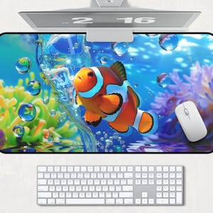 May include: A colorful mousepad with an orange and white clownfish swimming through blue water with bubbles. The mousepad has a black border.
