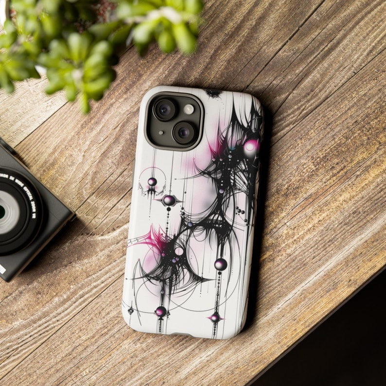 Op de afbeelding: Een witte telefoonhoes met een abstract ontwerp in zwart en roze. Het ontwerp bevat draaiende lijnen en cirkels met een roze en zwarte kleurstelling.