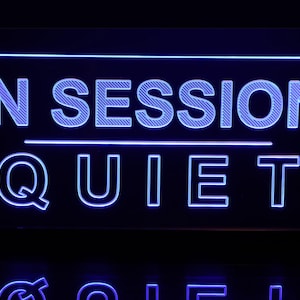 May include: Blue neon sign with the text "IN SESSION QUIET" in a white outline.