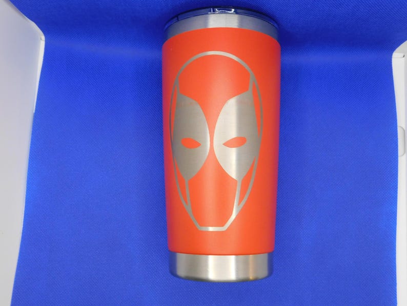 May include: A red stainless steel tumbler with a silver lid and a silver Deadpool mask design.
