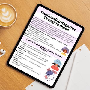 May include: A digital tablet displays a "Challenging Negative Thoughts Guide." The guide offers steps to spot and reframe unhelpful thoughts, with illustrations and bullet points. A cup of coffee and earbuds are on the wooden surface.