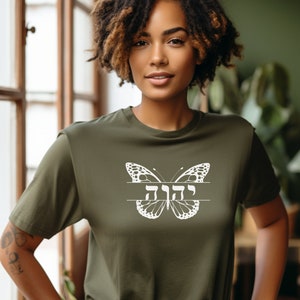 May include: A green t-shirt with a white butterfly graphic and the Hebrew word "Chayah" written across the butterfly's wings.