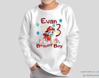May include: White long-sleeve shirt with a red and white cartoon dog, balloons, and the text "Evan 3 Birthday Boy".
