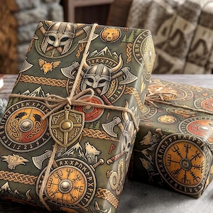 May include: Two rectangular gift boxes wrapped in olive green paper featuring a repeating pattern of Viking helmets, axes, shields, wolves, and bears. The boxes are tied with brown twine and adorned with a small, metallic, shield-shaped charm.