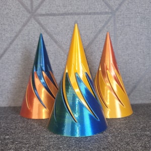 May include: Three decorative cone-shaped ornaments. The ornament on the left is orange and yellow. The ornament in the centre is blue and yellow. The ornament on the right is orange and yellow.