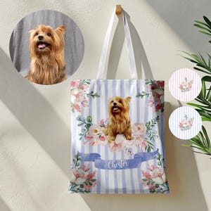 Op de afbeelding: Een witte tote bag met blauwe strepen en een bloemenontwerp. De tas heeft een gepersonaliseerde naam "Chester" en een afbeelding van een Yorkshire Terrier.