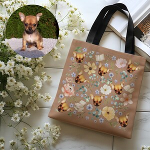 May include: A brown tote bag with black handles features a repeating pattern of a dog's face and floral designs. The dog's face is a chihuahua with brown fur.