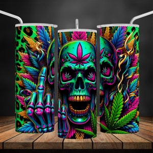 Puede incluir: Juego de tres vasos de acero inoxidable con un diseño llamativo. Cada vaso presenta una calavera verde neón con hojas de cannabis, un gesto de dedo medio y detalles dorados. El fondo incluye un estampado de leopardo y follaje colorido.